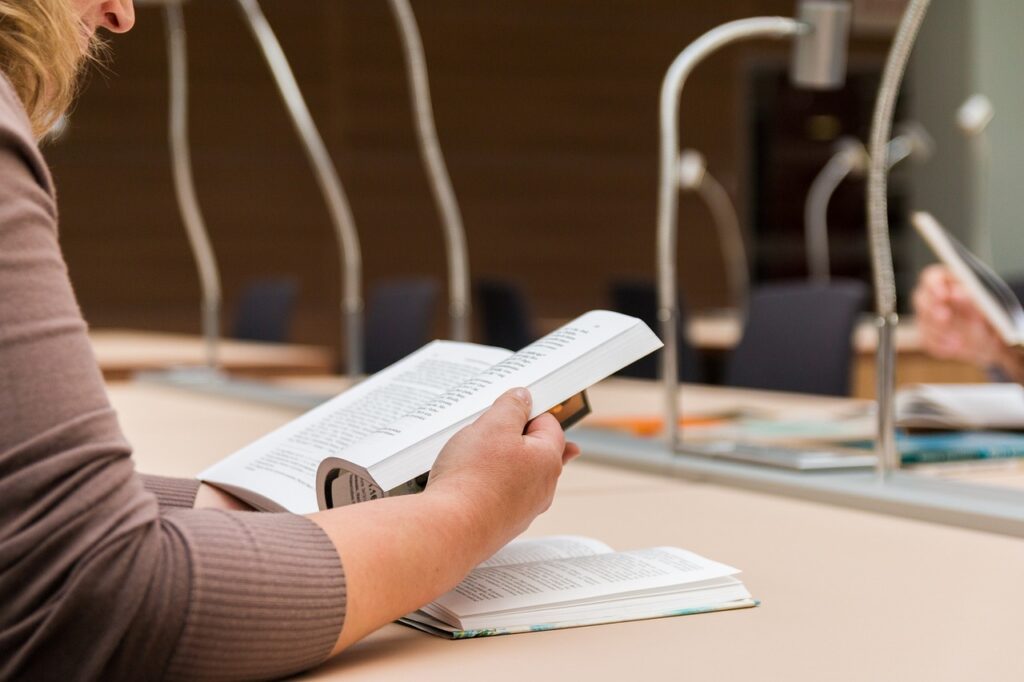 Student revising from a Test Prep book in a library.